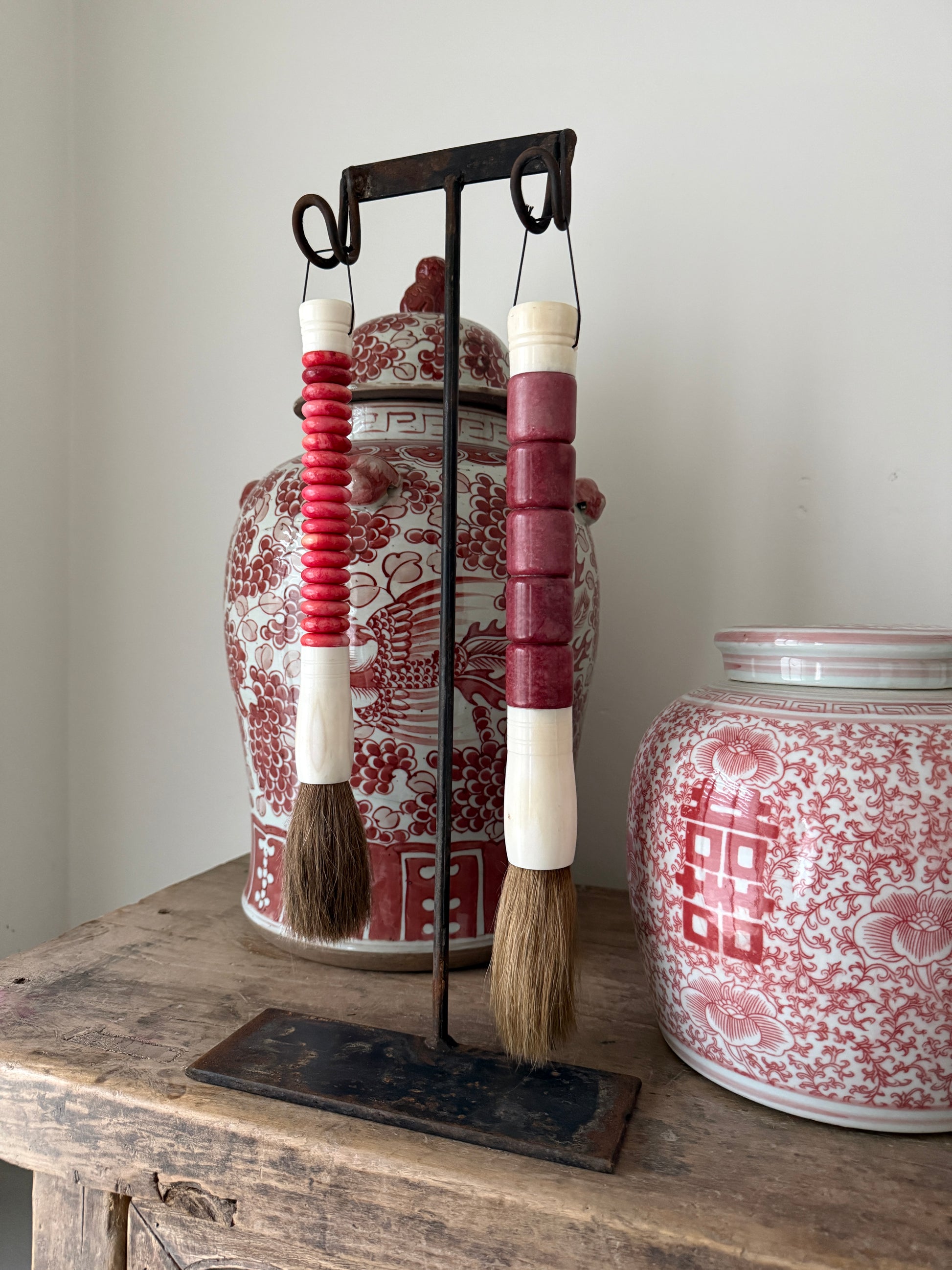 Twee roze kwasten op metalen standaard, voor rood-witte porseleinen potten, landelijk interieur