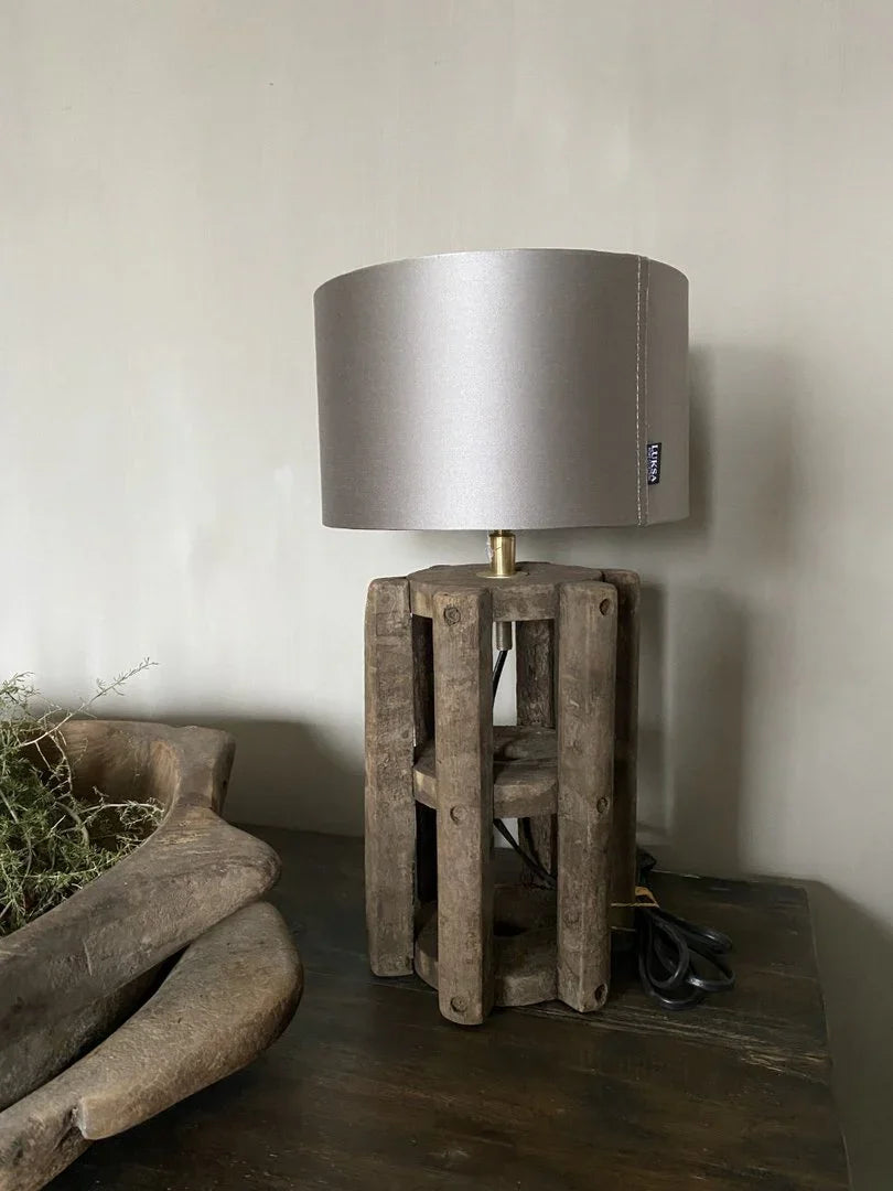 Authentieke houten tafellamp met stoffen kap op donkere tafel, landelijk sober interieur