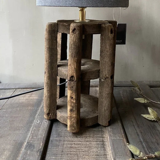 Handgemaakte lamp met robuuste houten basis en grijze katoenen kap, landelijk interieur