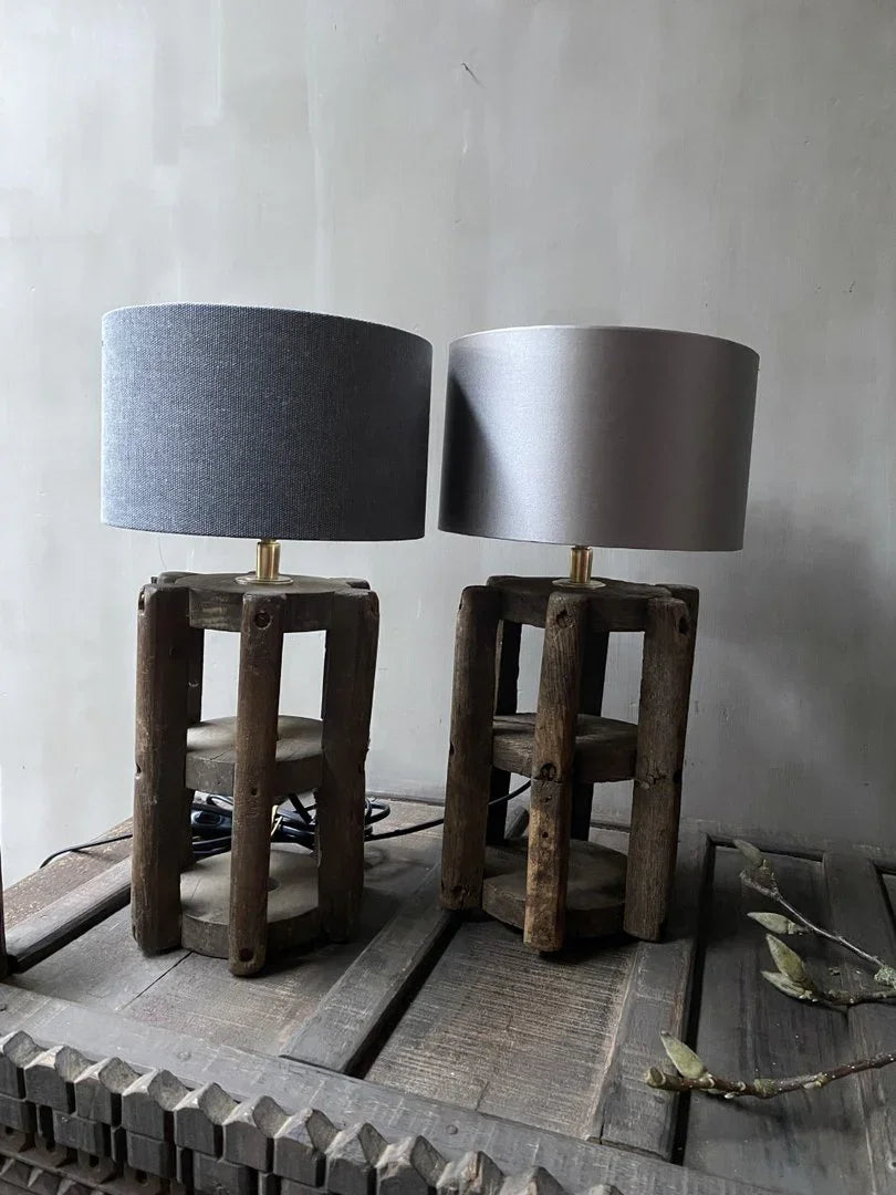 Twee handgemaakte tafellampen met houten voet en linnen kap op een sobere, landelijke tafel