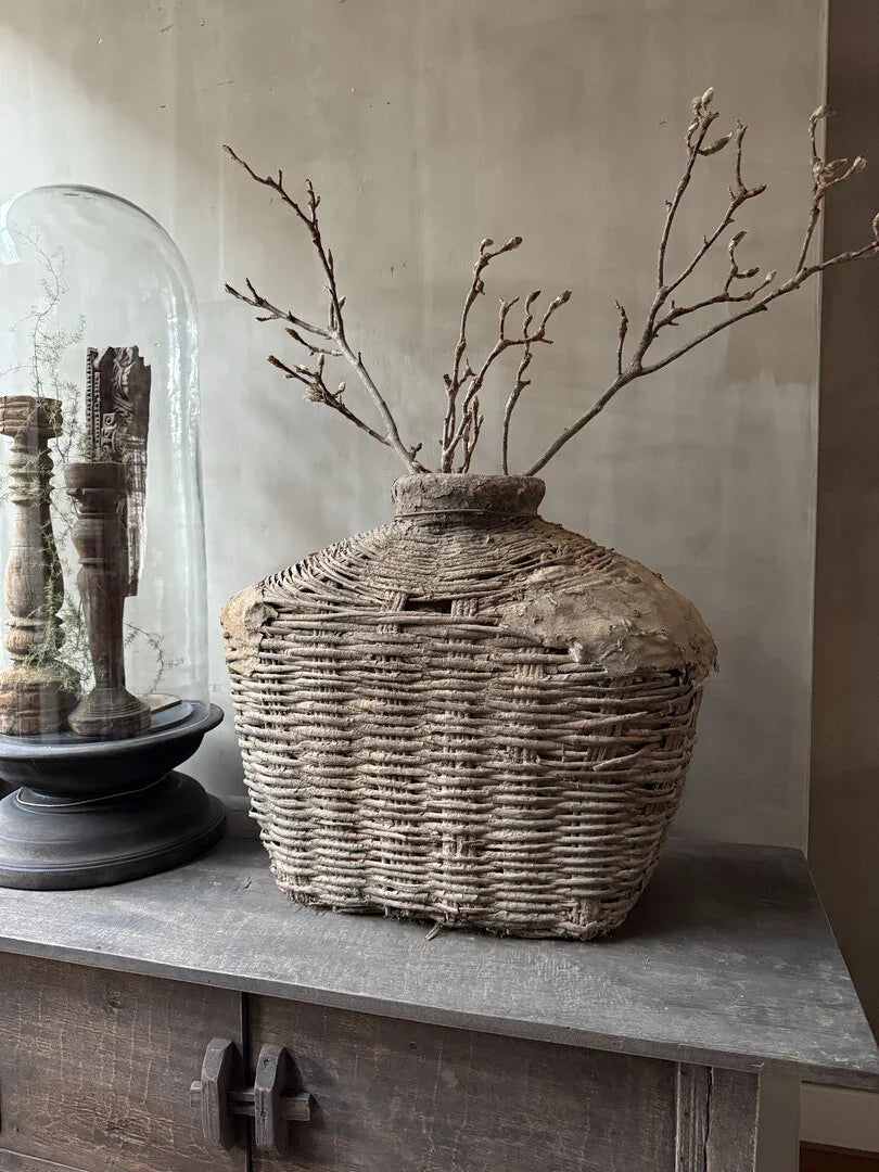 Authentieke handgemaakte leemmand met takken op rustieke kast, landelijk sober interieur