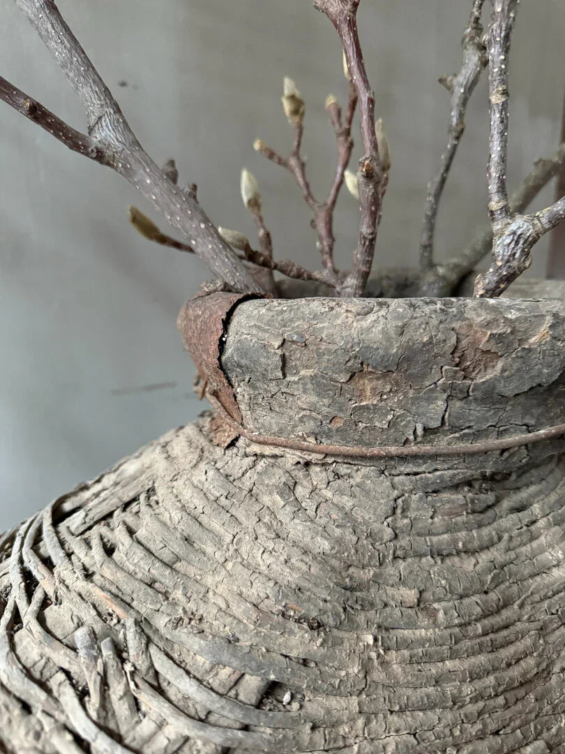 Detail van authentieke, handgemaakte leemmand met takken in sober landelijk interieur