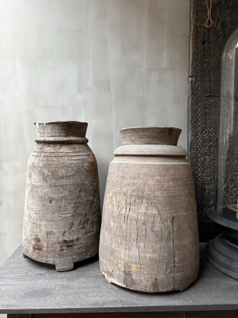 Twee authentieke houten Naga potten uit India, handgemaakt en sober, op een houten tafel.