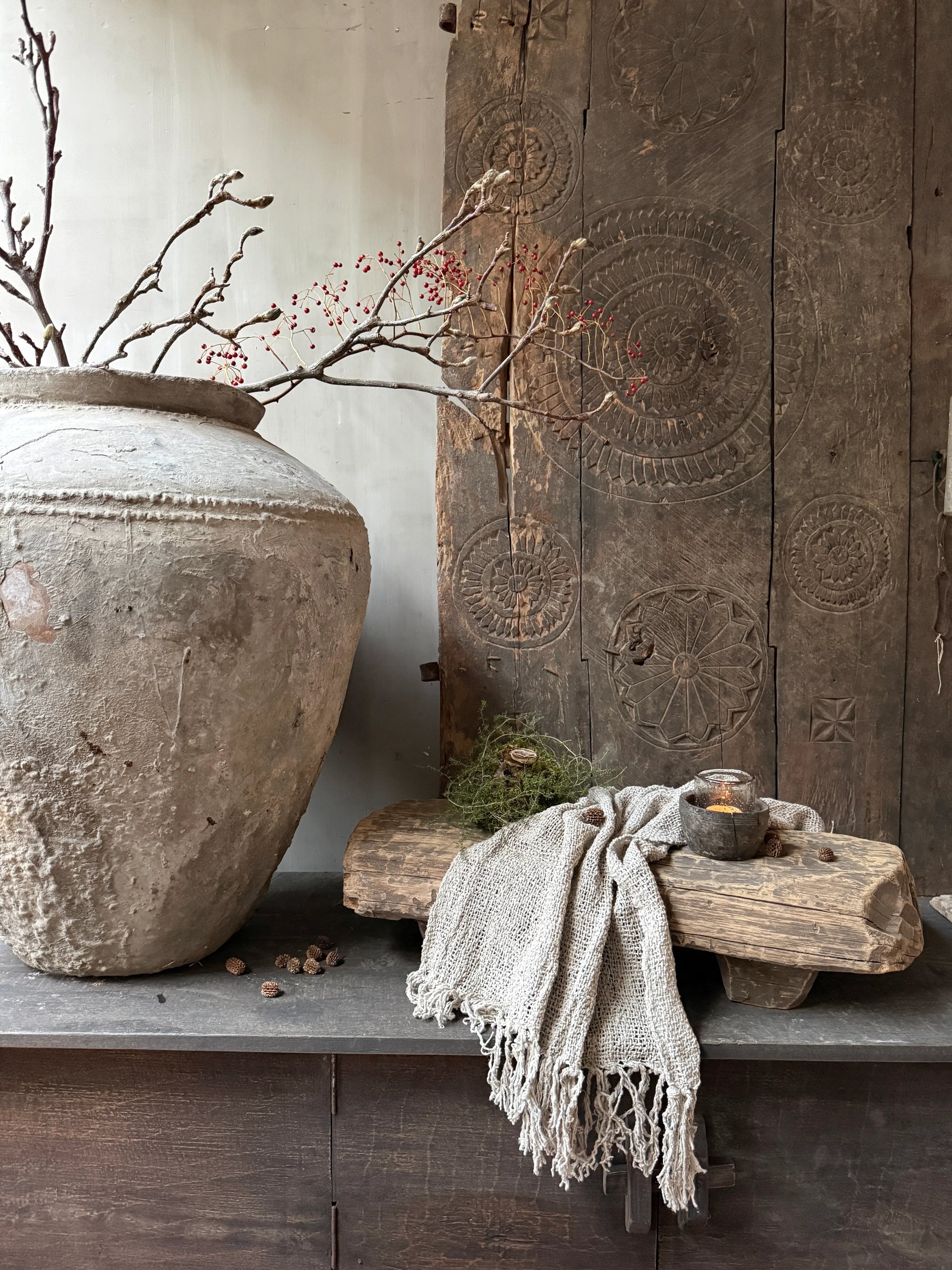 Sober landelijke woondecoratie met grote kruik, houten nagatafel, takken en handgemaakte accessoires