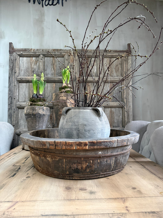 Authentieke houten olijfbak met grijze pot en takken op een landelijke eettafel, My Sober Home woonaccessoire