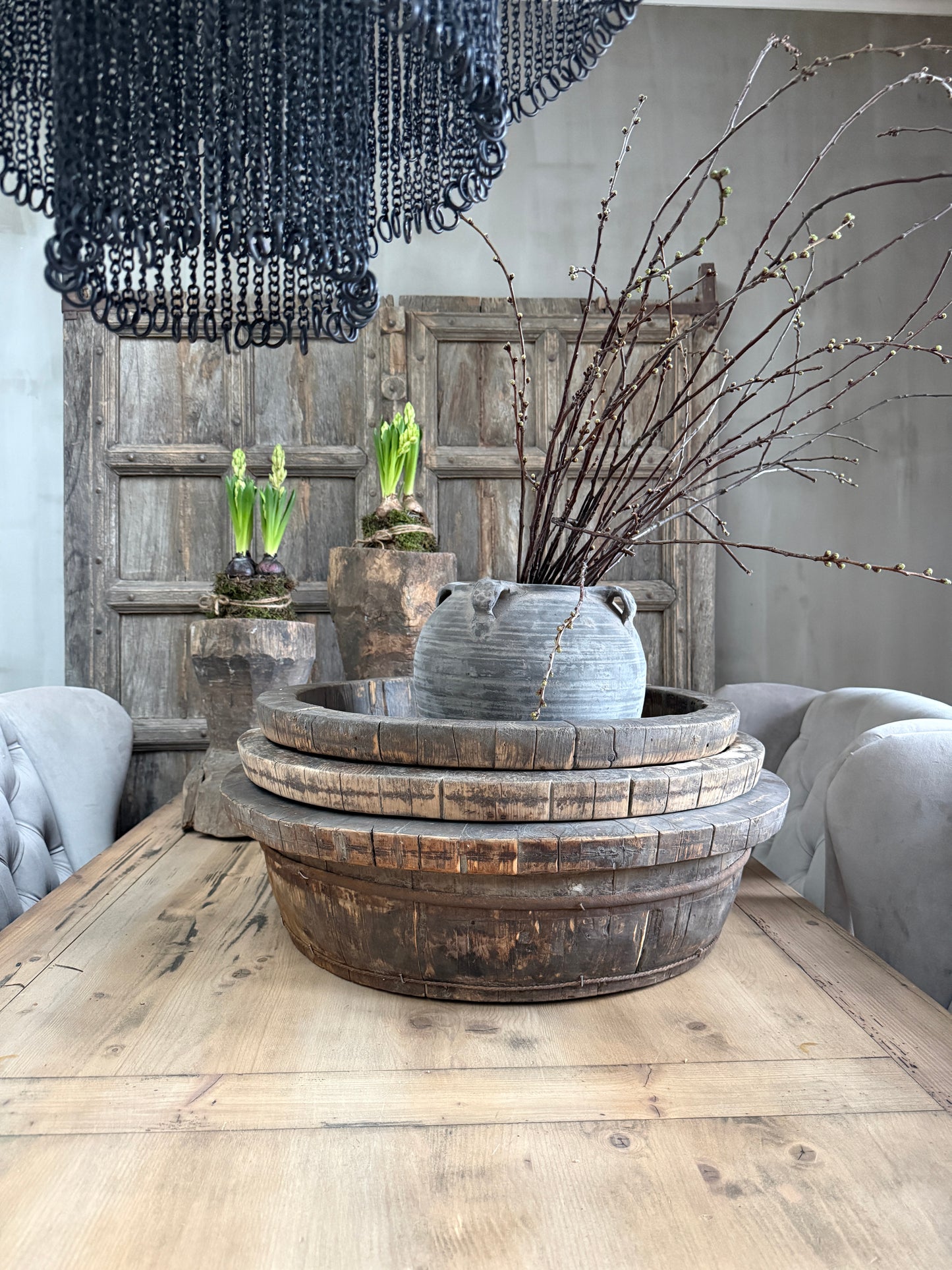 Authentieke houten olijfbak met handgemaakt aardewerk en takken op landelijke eettafel