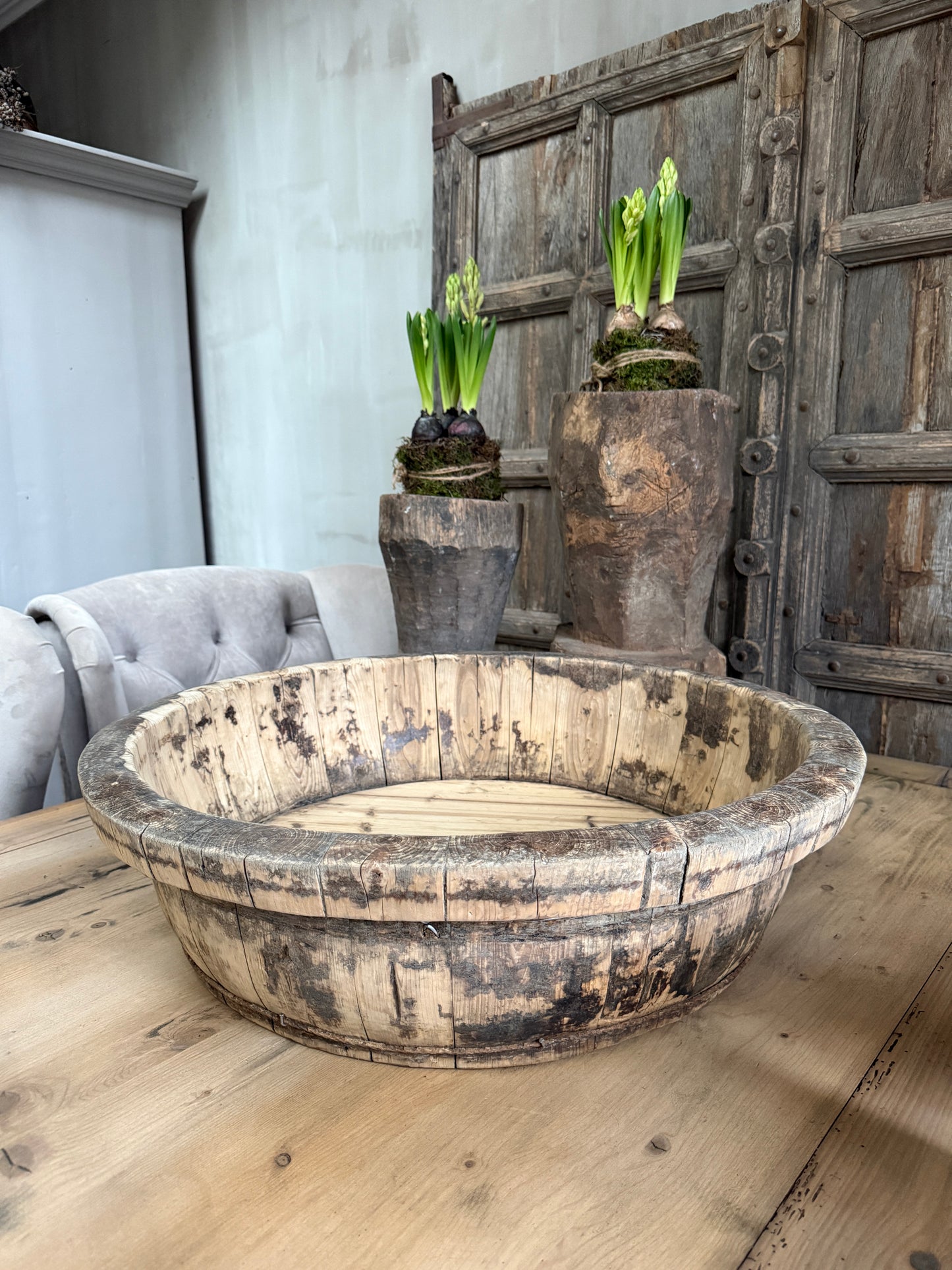 Authentieke houten olijfbak op houten tafel in sober, landelijk interieur met plantenpotten