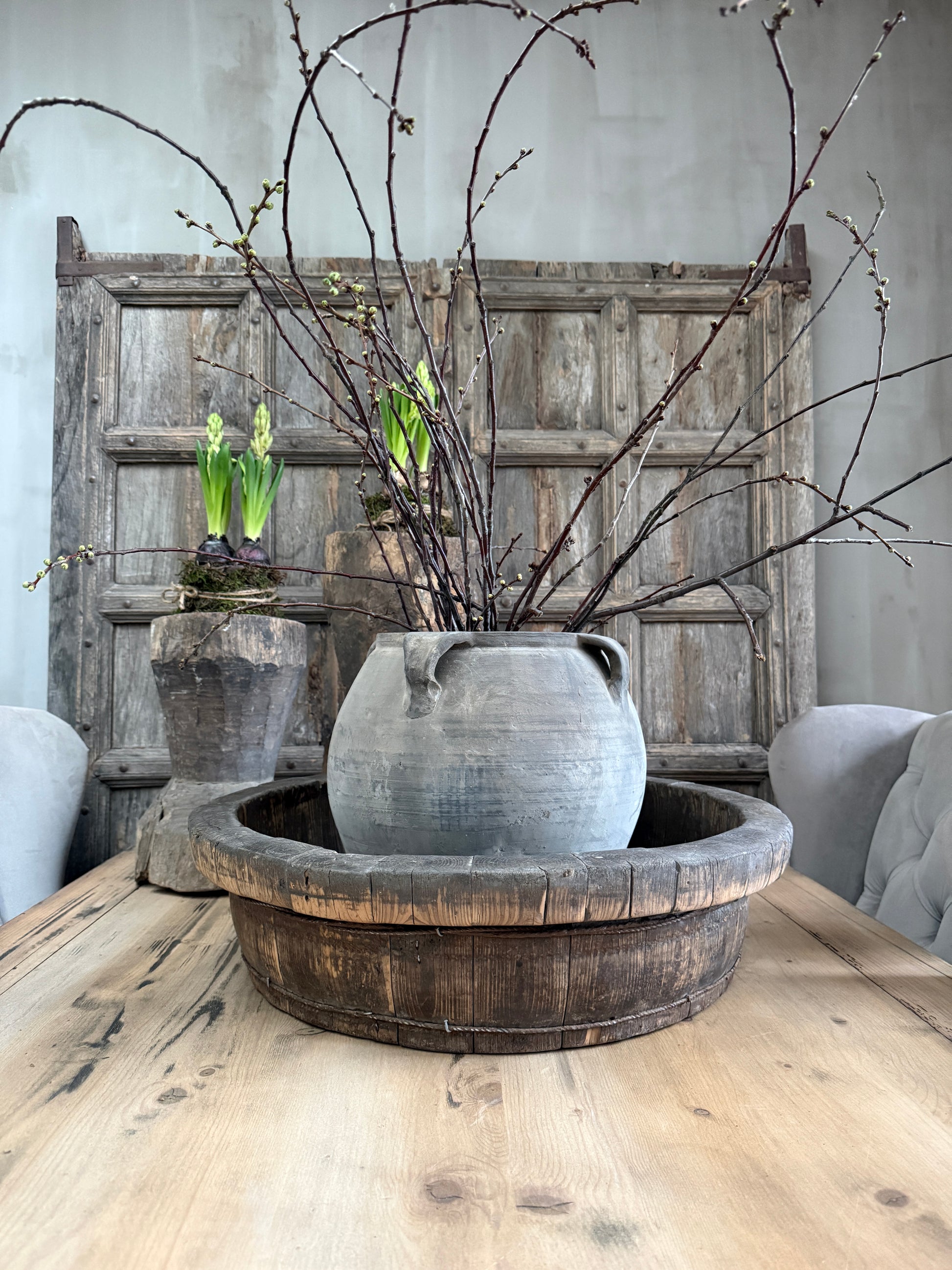 Authentieke houten olijfbak met rustieke vaas en takken op houten tafel, landelijk interieur