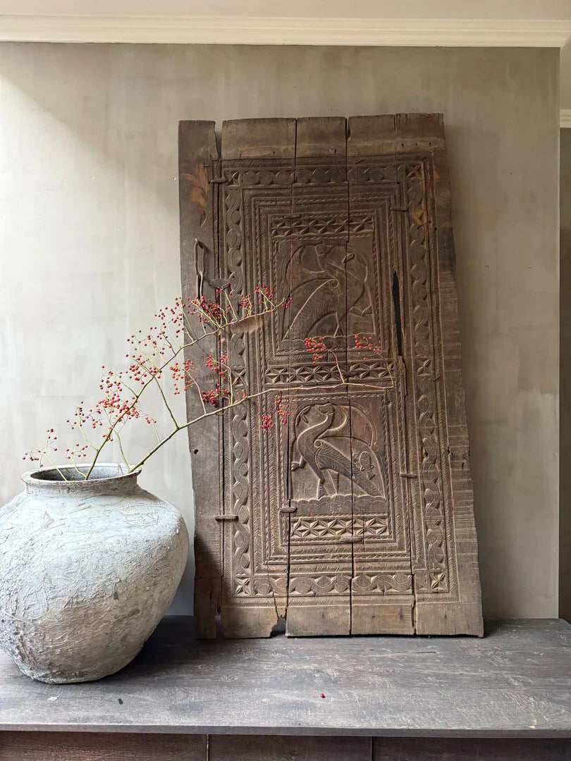 Authentieke houten paneel uit India met vogelmotief en landelijke kruikvaas, sober interieur