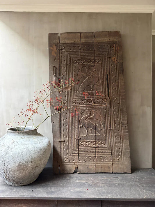 Authentieke houten paneel uit India met vogelmotief en landelijke kruikvaas, sober interieur