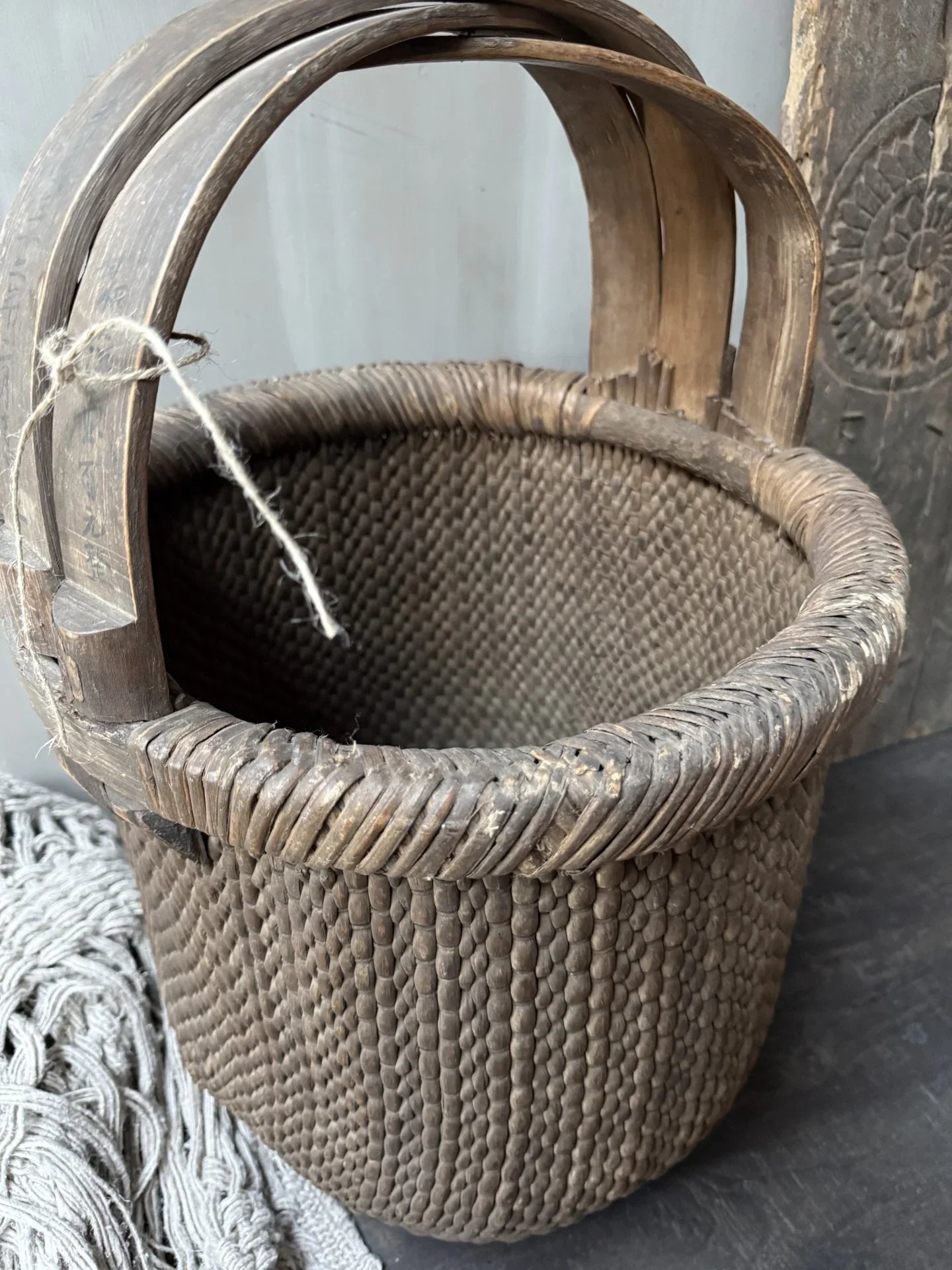 Authentieke handgemaakte rieten plukmand met houten handgrepen, sober landelijk interieur