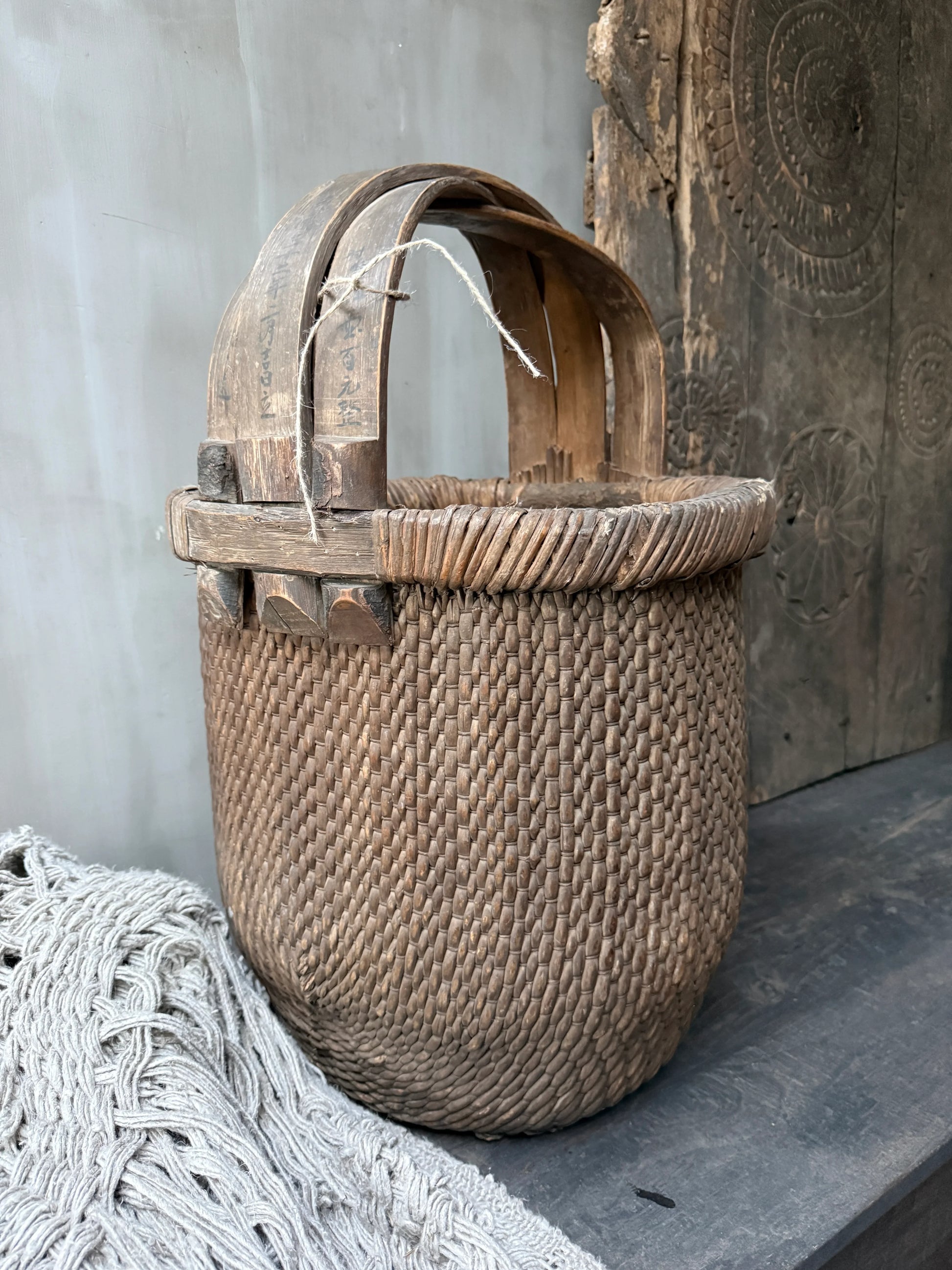 Authentieke handgemaakte plukmand van gevlochten riet en hout, landelijk sober interieur
