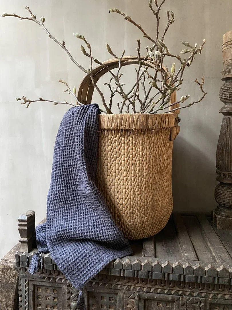 Handgemaakte plukmand met droogtakken en donkerblauwe doek, landelijk sober interieur
