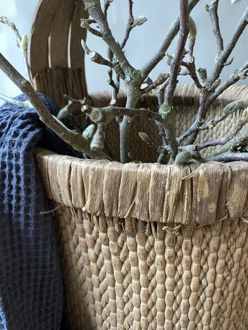 Authentieke handgemaakte plukmand met takken en donkerblauwe doek, landelijk interieur