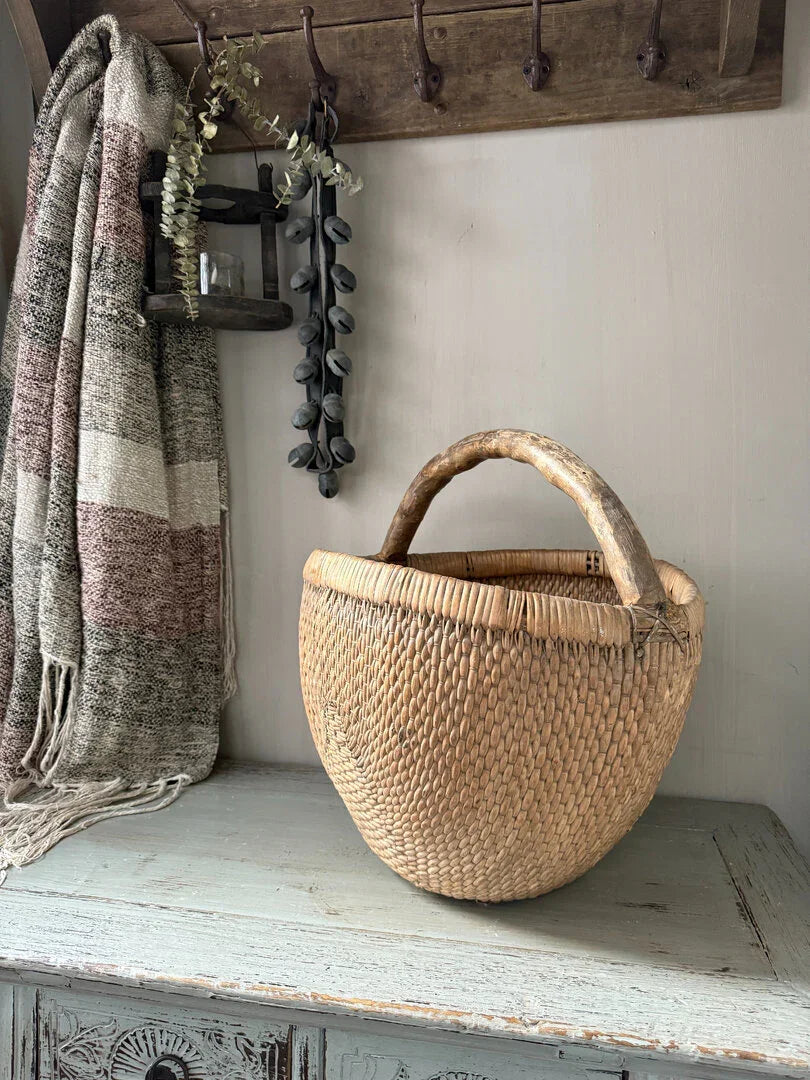 Handgemaakte plukmand met houten handvat op houten kast, landelijk en sober interieur decoratie.