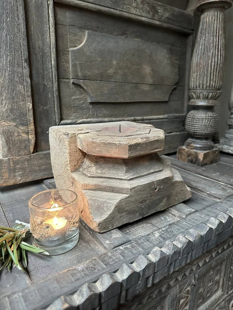 Authentieke houten kandelaar en glazen waxinelichthouder op sober landelijk interieurmeubel