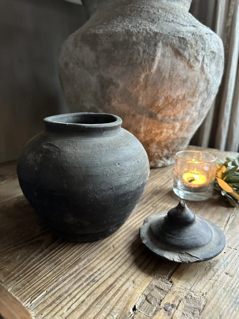 Authentiek, handgemaakt zwart potje met deksel op houten tafel, landelijk interieur