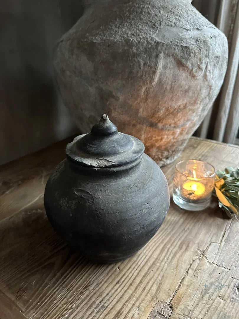 Authentiek zwart potje met deksel op houten tafel, landelijke en sobere woonaccessoire