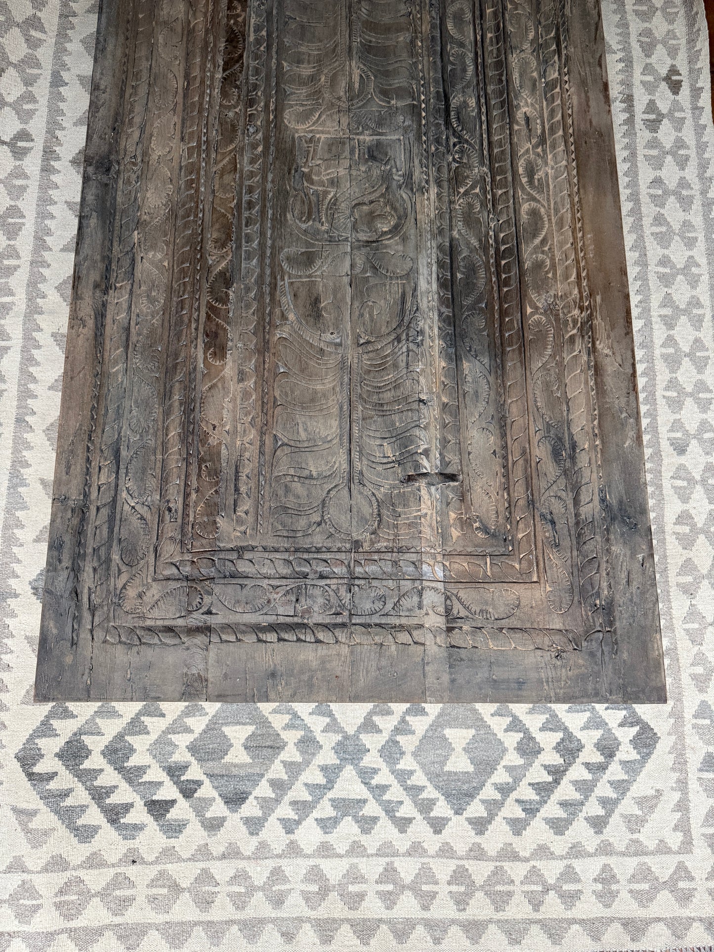 Handgemaakte houten salontafel met rustieke gravures op een beige vloerkleed met patroon, My Sober Home