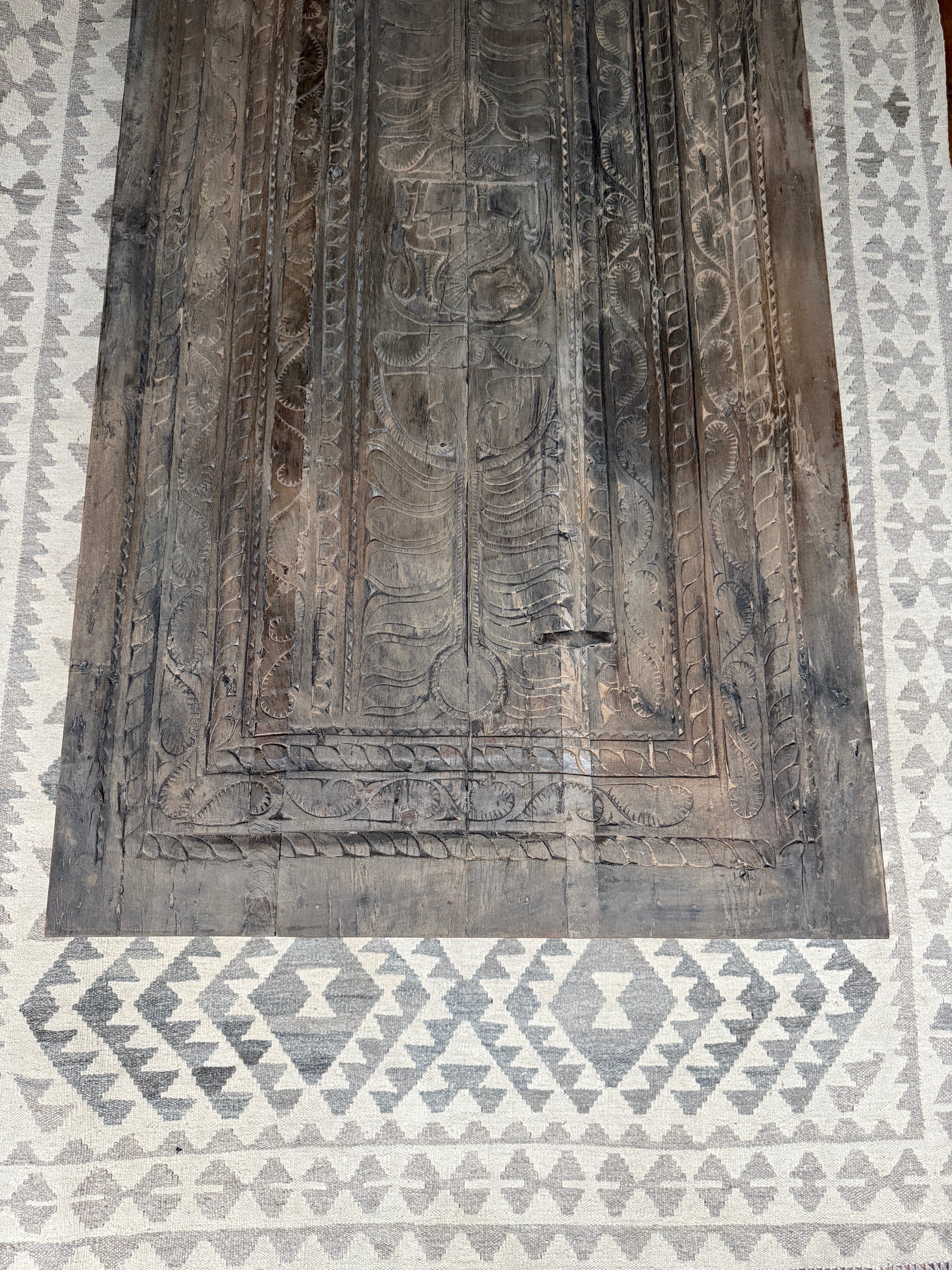 Handgemaakte houten salontafel met rustieke gravures op een beige vloerkleed met patroon, My Sober Home