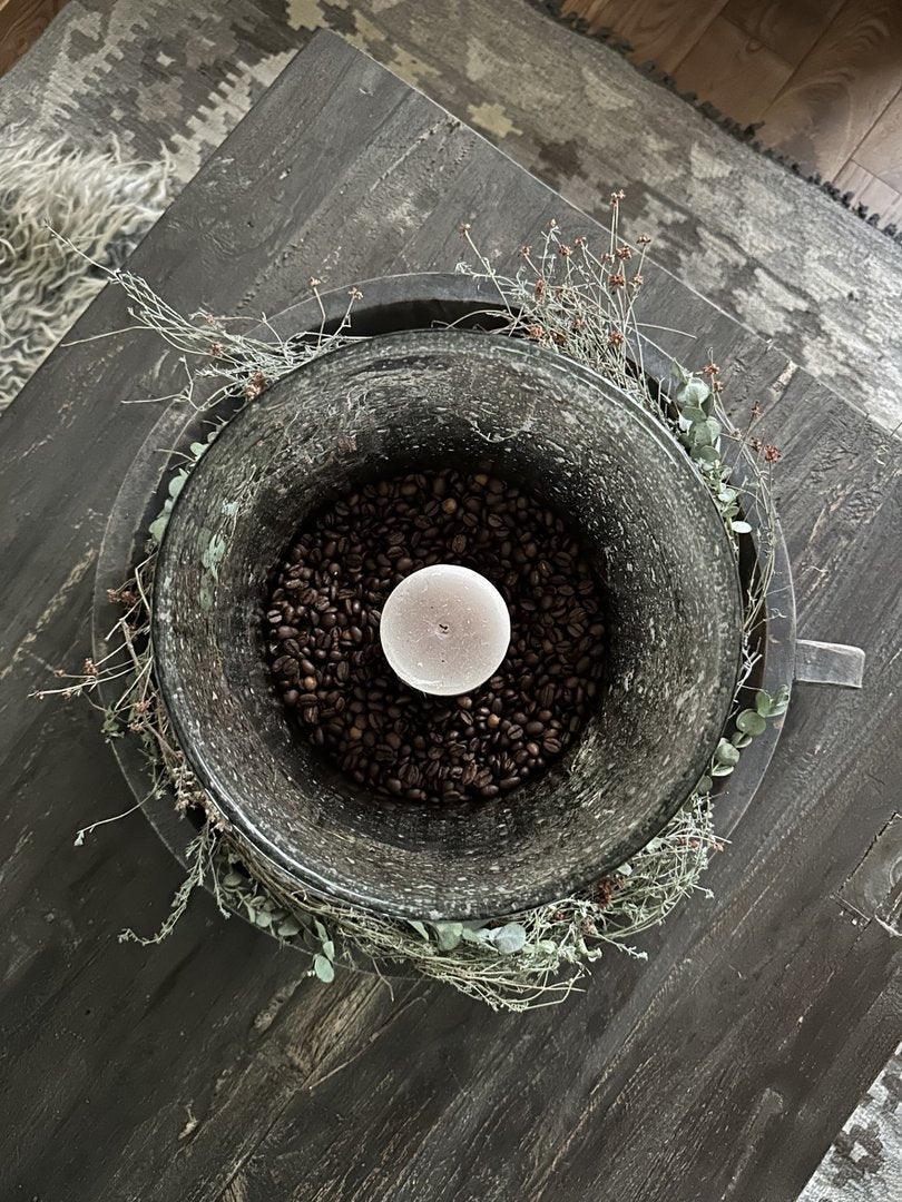 Handgemaakte schaal met handvat, gevuld met koffiebonen en een kaars, landelijk interieur