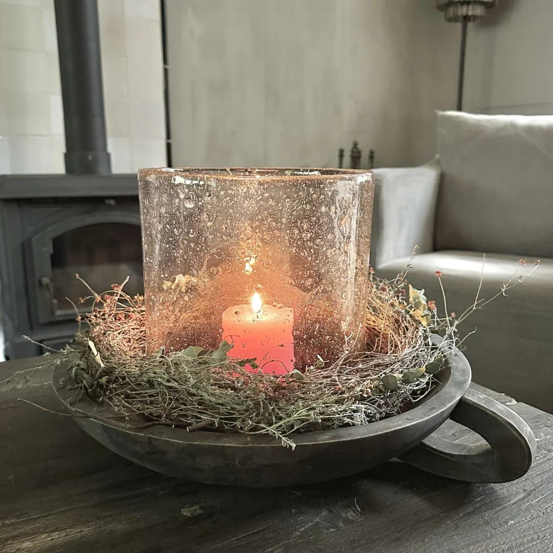 Stoere, handgemaakte schaal met handvat, windlicht en kaars in sober landelijk interieur