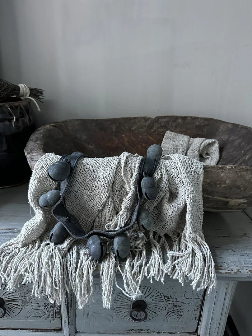 Handgemaakte schapenbel decoratie op landelijke houten kast met grof linnen plaid, sober interieur