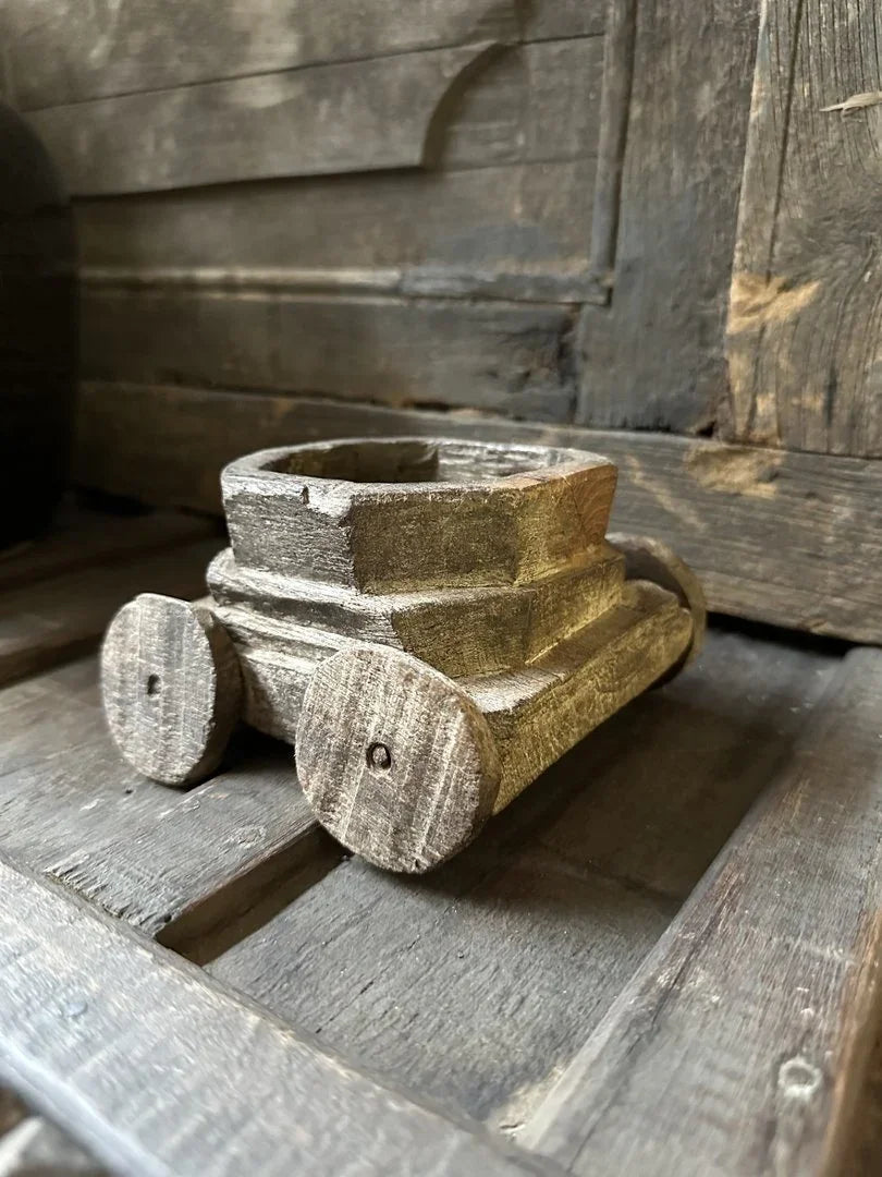 Handgemaakt houten speelgoedwagentje op rustieke achtergrond, sober landelijk interieur