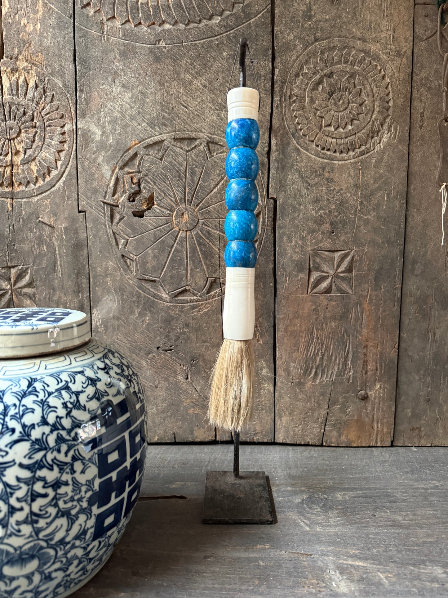 Handgemaakte decoratieve kwast met blauwe kralen en keramische pot, sober landelijk interieur