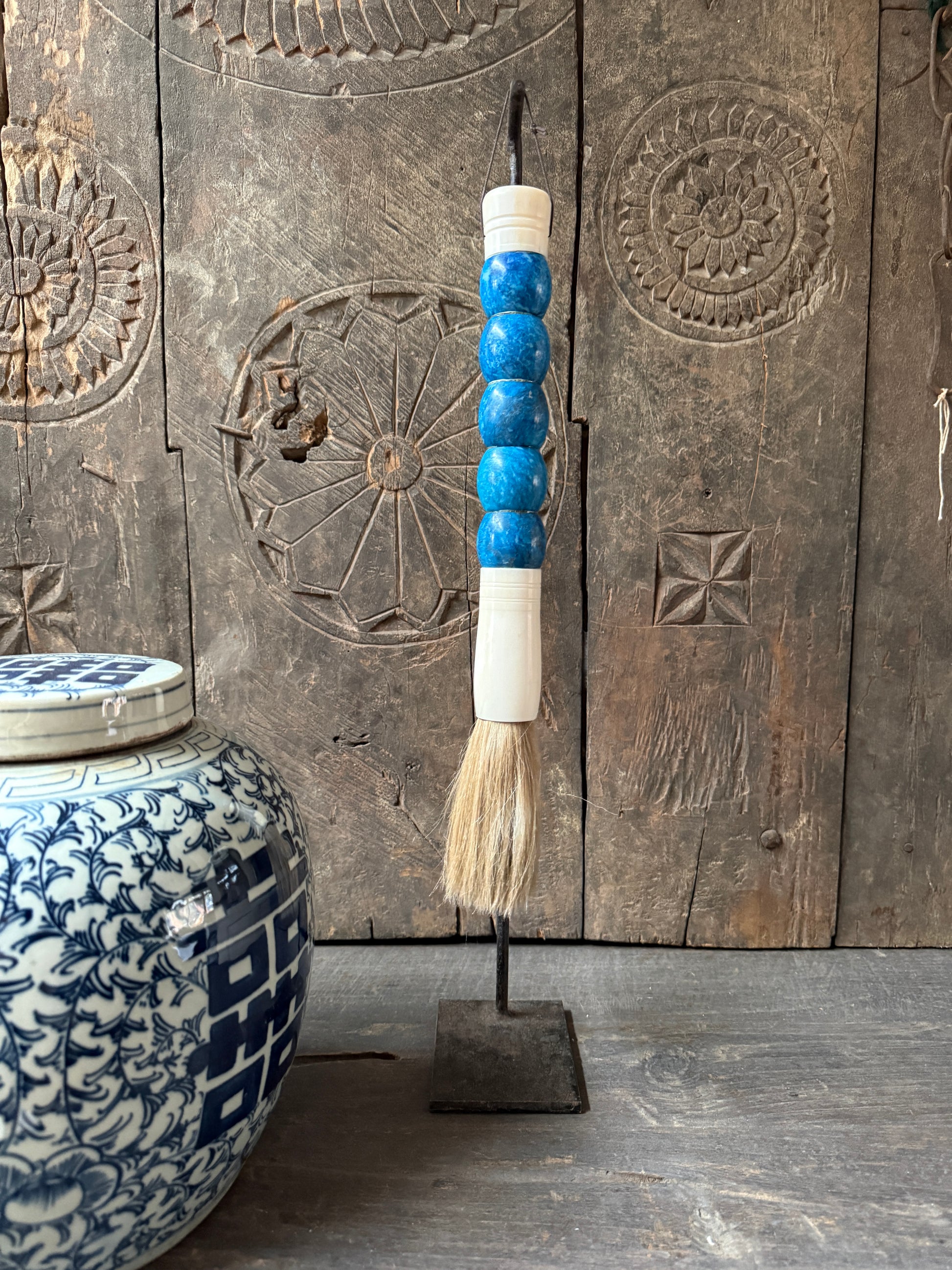 Handgemaakte decoratieve kwast met blauwe kralen en keramische pot, sober landelijk interieur