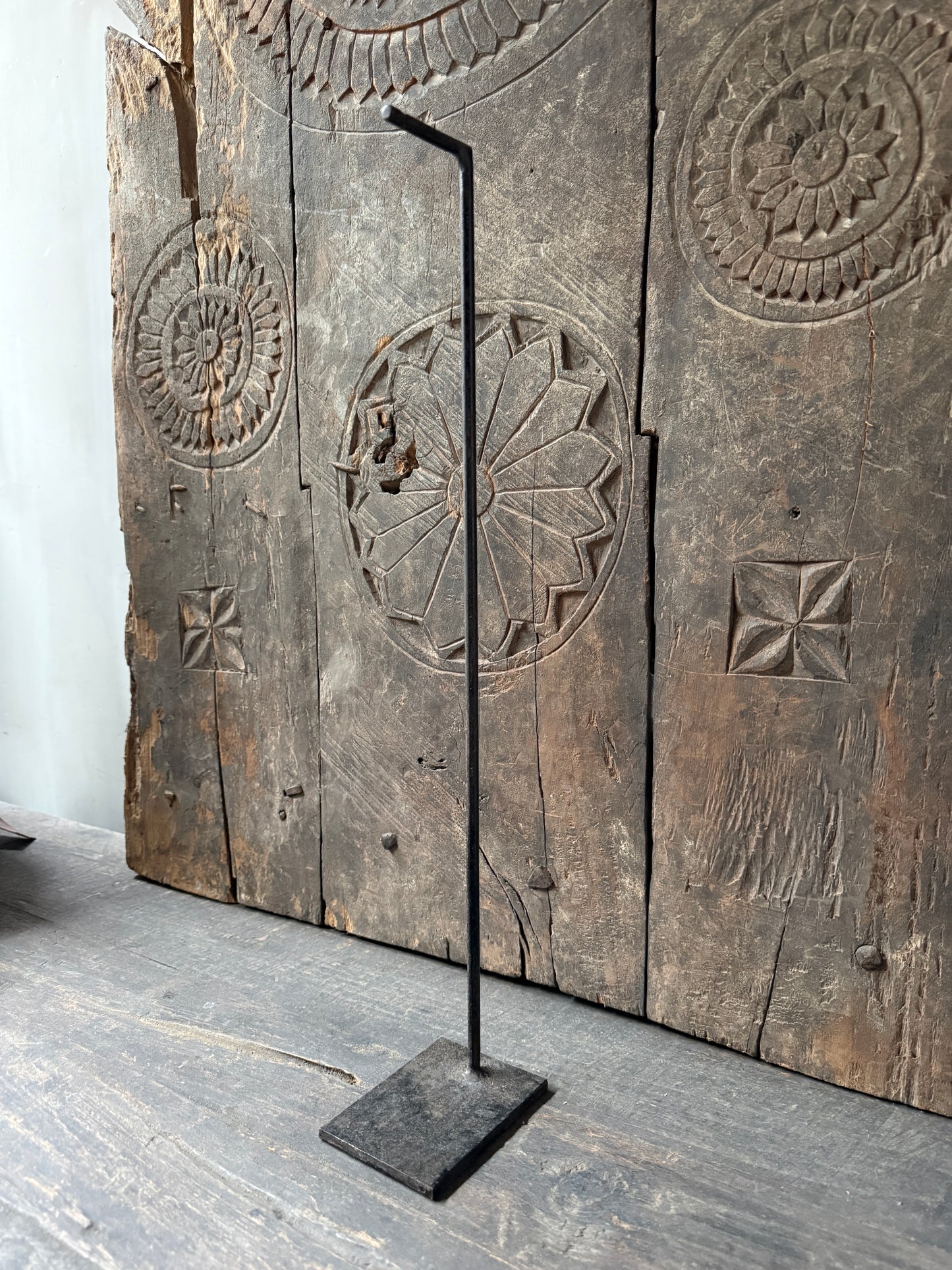 Handgemaakte zwarte metalen standaard op verweerd houten oppervlak, landelijk en sober interieur