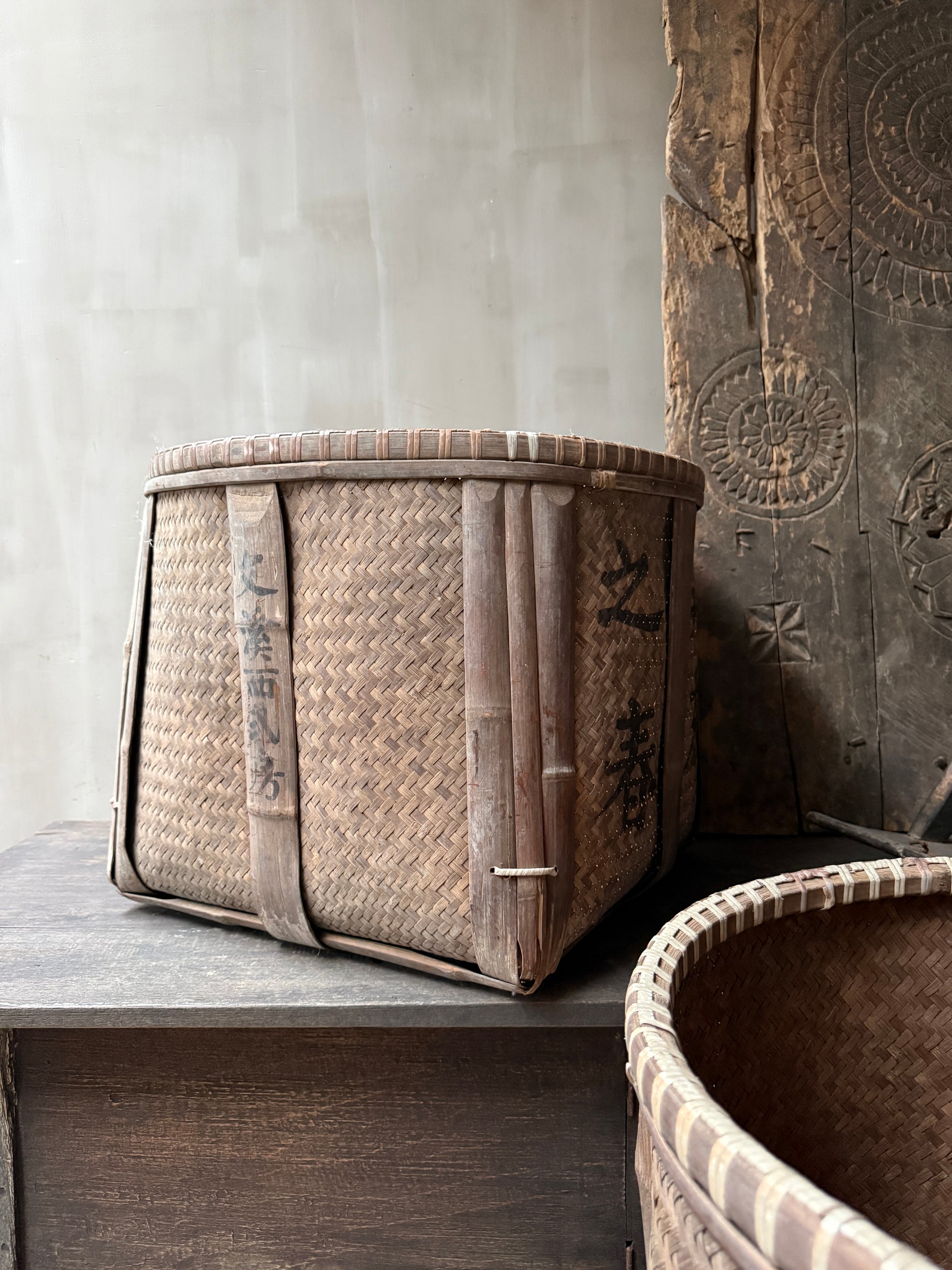 Handgemaakte vierkante mand van gevlochten riet, authentiek woonaccessoire in sober, landelijk interieur