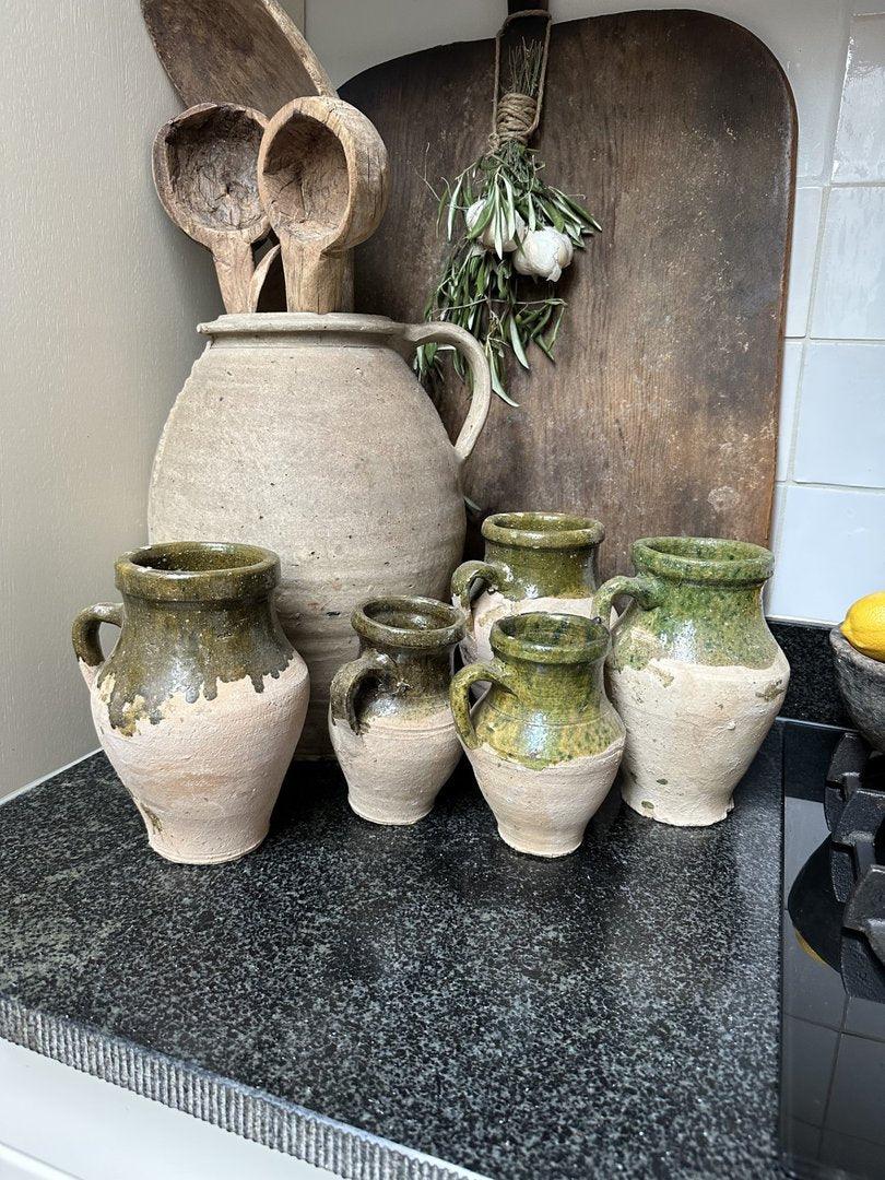 Authentieke handgemaakte aardewerken kruikjes en houten lepels op zwart aanrecht, landelijk interieur