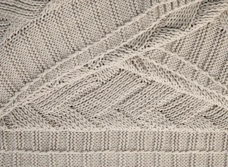 Close-up van handgemaakt, beige gebreid woonaccessoire met uniek patroon uit My Sober Home.