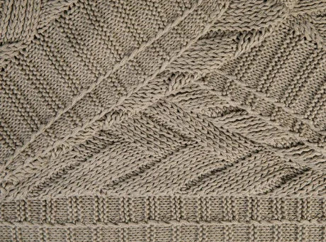 Close-up van handgemaakt beige breiwerk met patroon, landelijke woonaccessoire My Sober Home