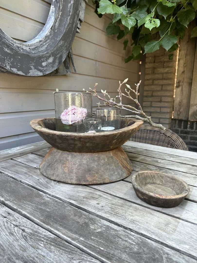 Handgemaakte houten vijzel en schaal op landelijke houten tuintafel, sobere woondecoratie