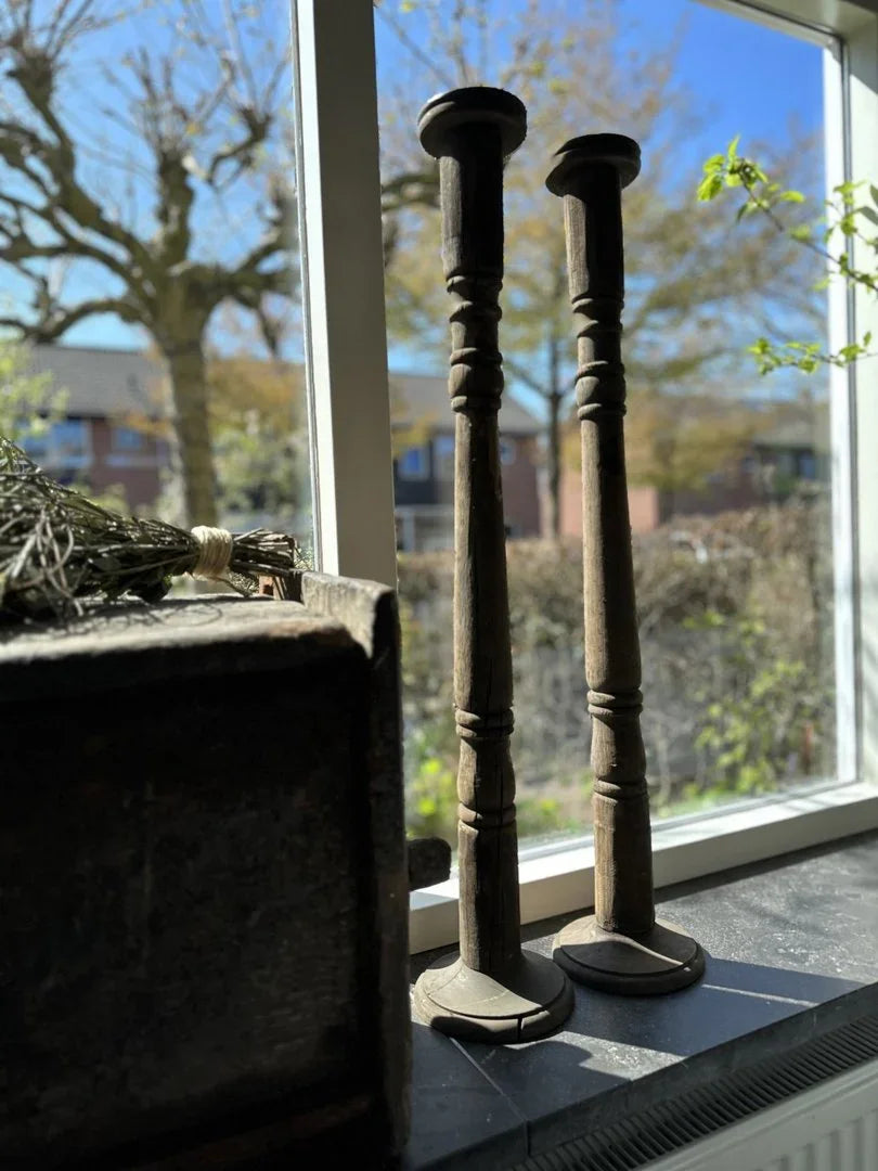 Twee handgemaakte houten vloerkandelaars op een vensterbank, landelijke woonaccessoires