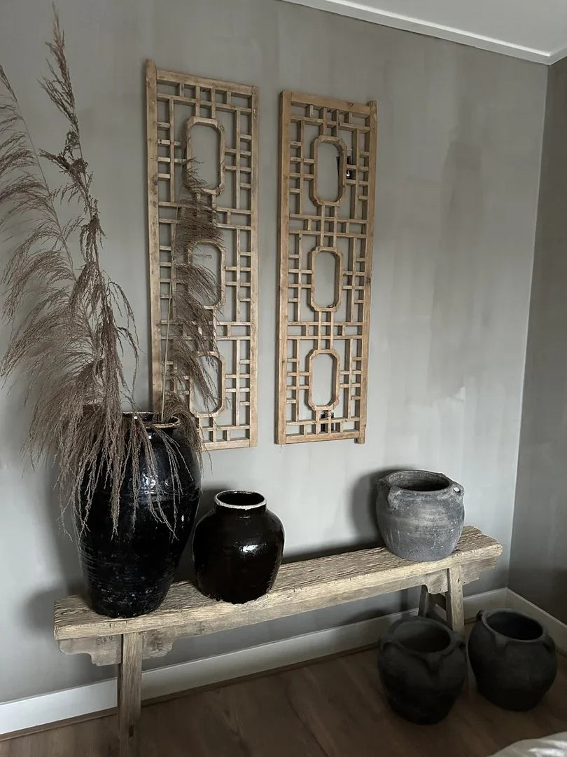 Sober landelijk interieur met houten wandpanelen, robuuste kruiken en houten bankje.