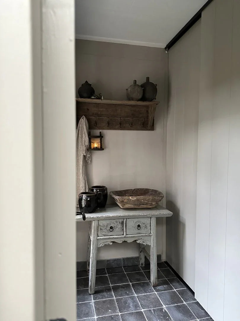 Landelijke wandtafel met handgemaakte accessoires en houten schaal in sober interieur