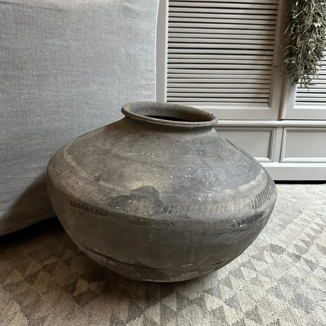Handgemaakte, authentieke XL wankelpot van grijs aardewerk op vloerkleed in sober interieur