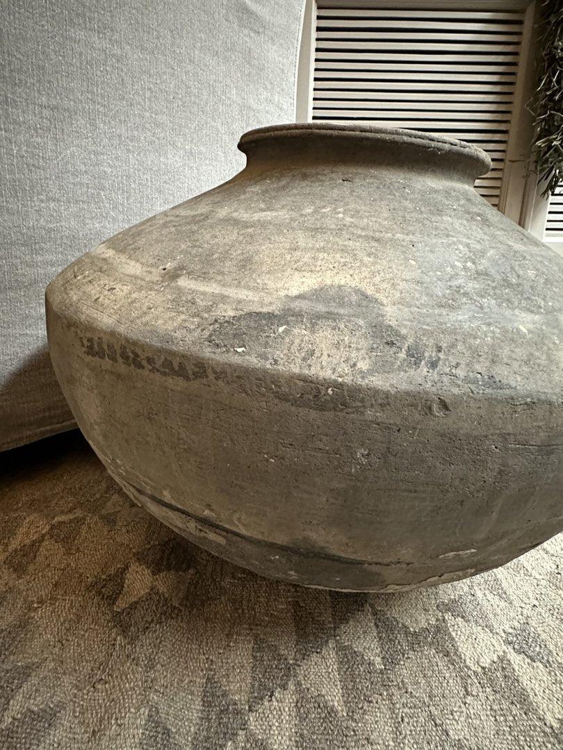 Grote, handgemaakte Wankelpot vaas van aardewerk, sober en authentiek, op landelijk vloerkleed