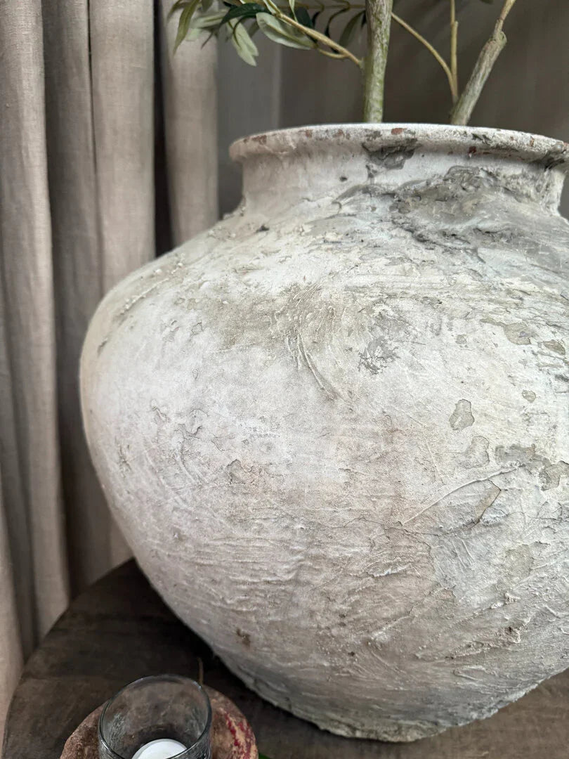 Authentieke handgemaakte waterkruik van aardewerk met grove textuur, sober landelijk interieur