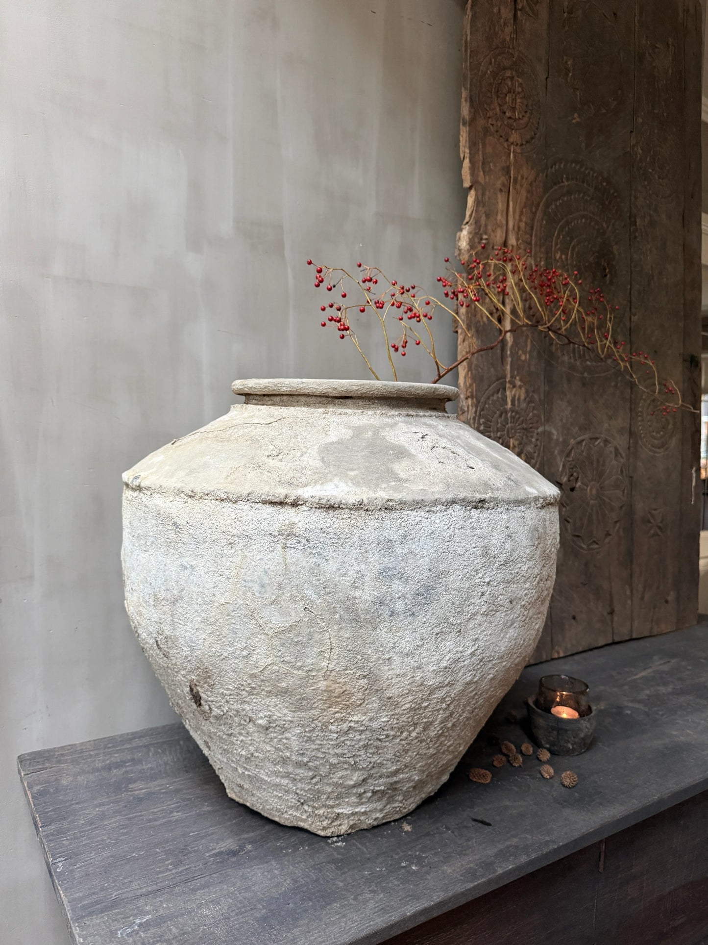 Authentieke, handgemaakte waterpot met tak en rode bessen, landelijk sober interieur