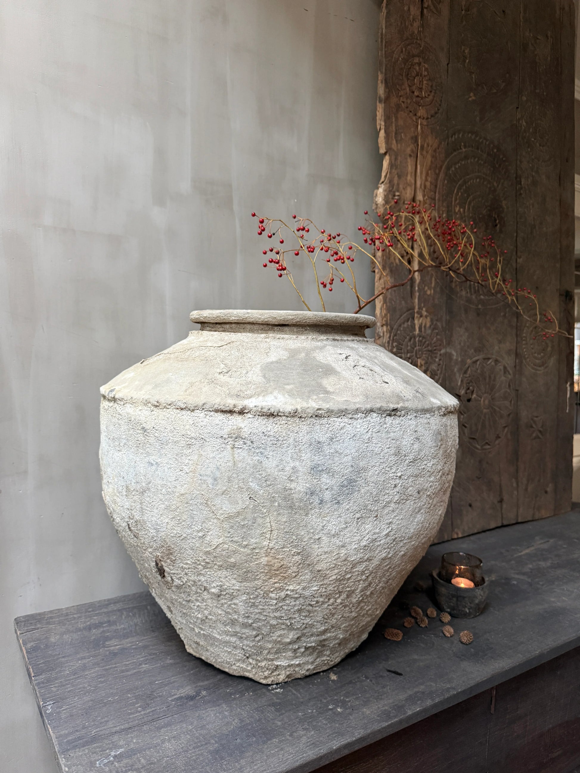 Authentieke, handgemaakte waterpot met tak en rode bessen, landelijk sober interieur