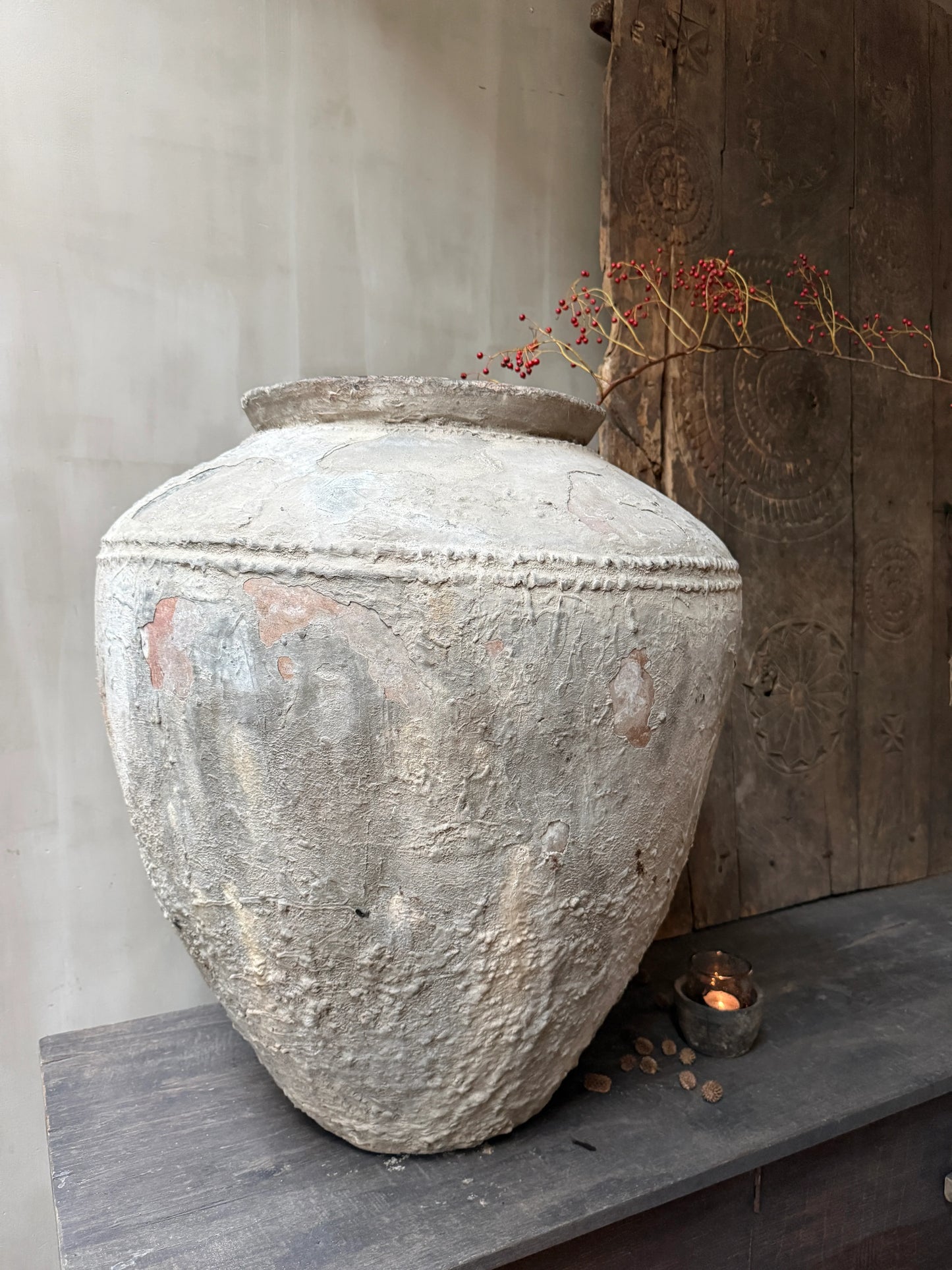 Authentieke, handgemaakte waterpot van klei met tak en besjes, sober landelijk interieur