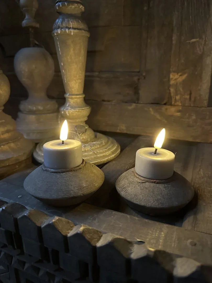 Grijze waxinelichthouders van hout met brandende kaarsen, landelijk sober interieur