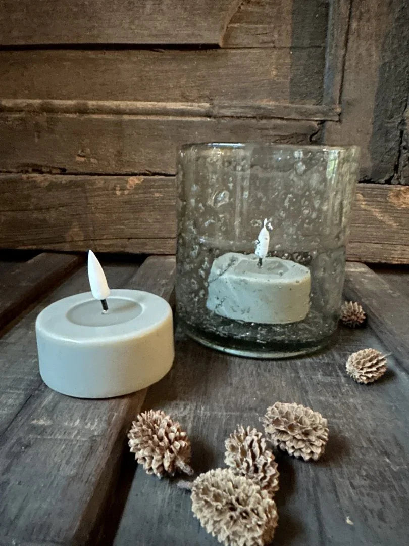 Handgemaakte waxinelicht zandkleurig in glas en op houten tafel, landelijke woondecoratie