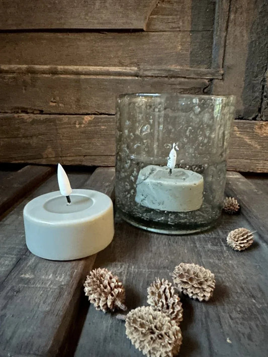 Handgemaakte waxinelicht zandkleurig in glas en op houten tafel, landelijke woondecoratie