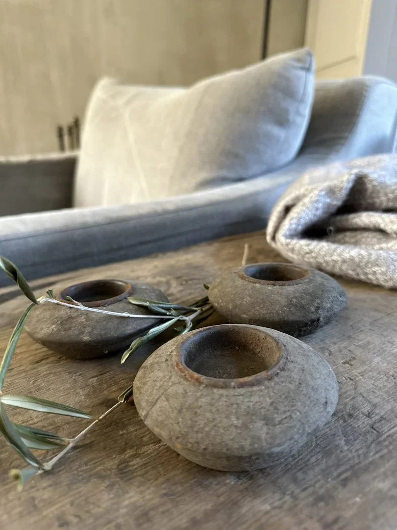 Handgemaakte, sobere waxinelichthouders van steen op houten tafel, passend bij landelijk interieur