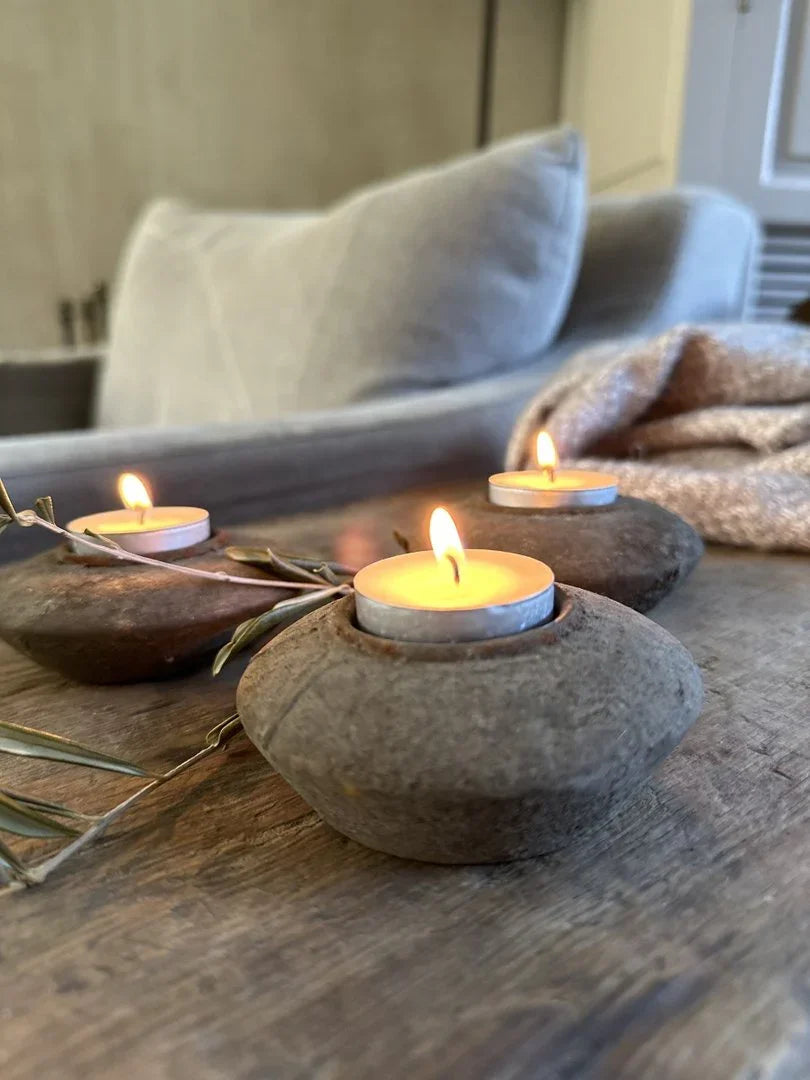 Handgemaakte waxinelichthouders van steen op houten tafel, sfeervol landelijk interieur.